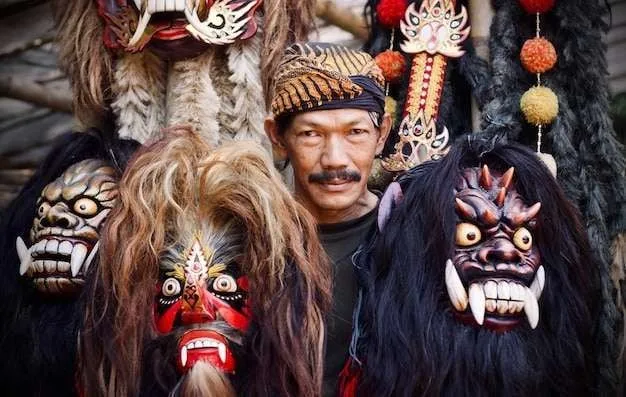 Seorang pengrajin menampilkan topeng tradisional Jawa yang digunakan dalam pertunjukan kesenian rakyat Reog dan Barong.