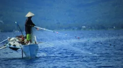 Ilustrasi seorang nelayan tengah mencari ikan di laut.