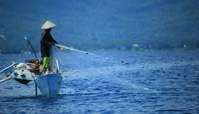Ilustrasi seorang nelayan tengah mencari ikan di laut.