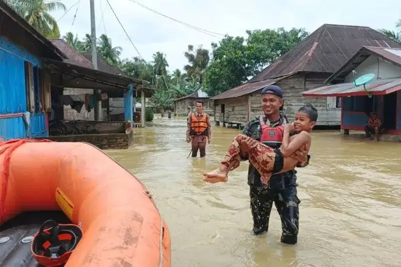 Seorang petugas mengevakuasi warga Rantau Panjang di Kecamatan Sasak Ranah Pasisia yang terjebak banjir, Selasa (25/11/2025).