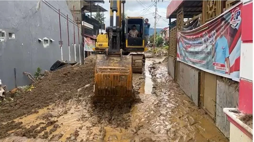 Excavator mengeruk lumpur yang terbawa banjir untuk membuka akses jalan di Kecamatan Nanggalo Korong Gadang, Kota Padang, Minggu (30/11/2025).