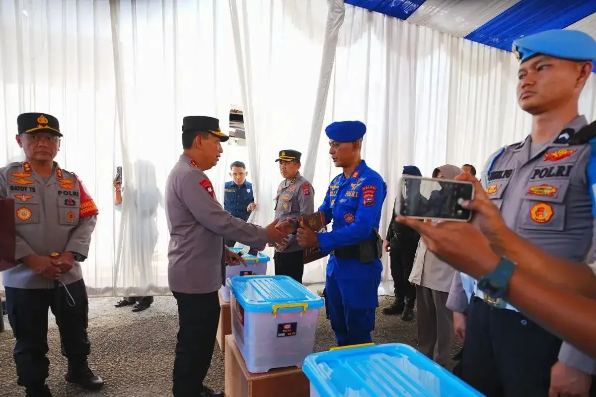 Kapolri Jenderal Pol. Listyo Sigit Prabowo (tengah) memberikan bantuan kemanusiaan untuk anggota Polri yang menjadi korban bencana banjir di Polsek Koto Tengah, Jalan Adi Negoro, Lubuk Buaya, Kota Padang, Sumatera Barat (Sumbar), Kamis (18/12/2025).