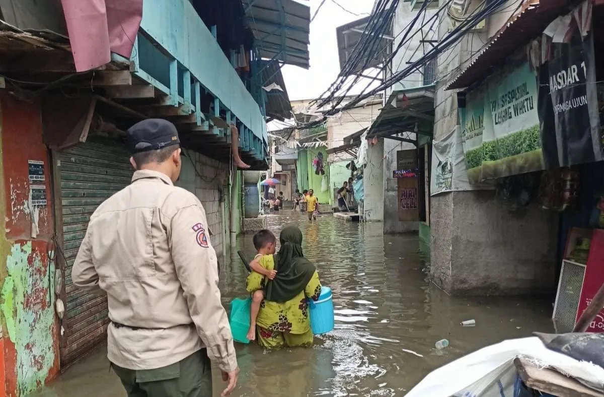 Seorang ibu menggendong anaknya nekat menerobos banjir rob di Penjaringan Jakarta Utara, Kamis (4/12/2025).