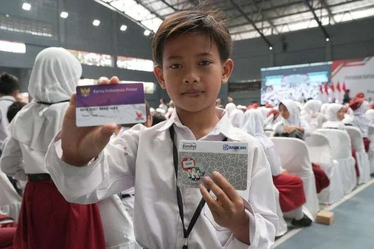 Seorang anak sedang memegang kartu Program Indonesia Pintar (PIP).